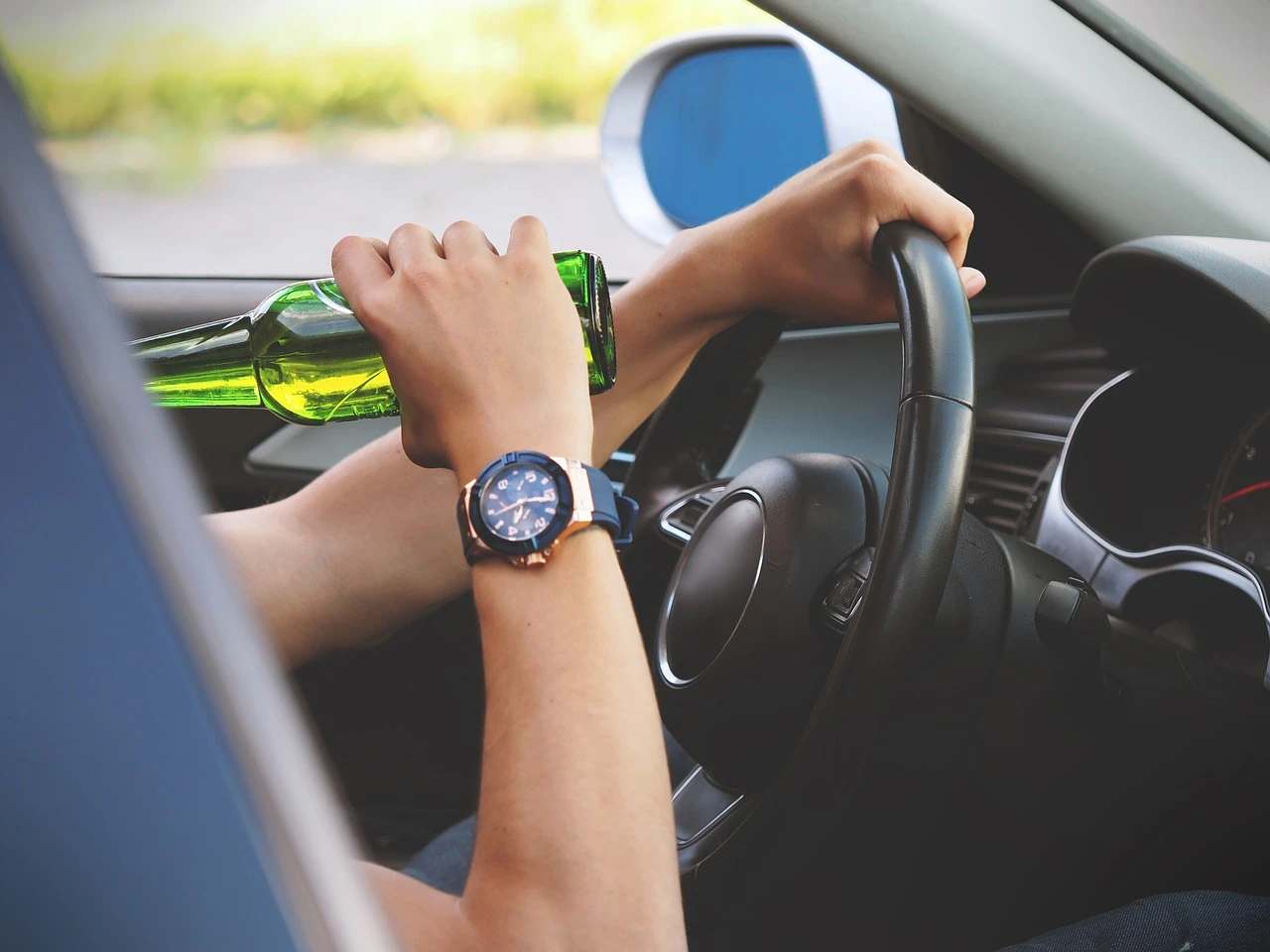 Person drinkt Alkohol am Steuer