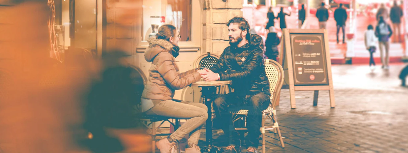 Ein Paar sitzt im Winter draußen vor einem Cafe