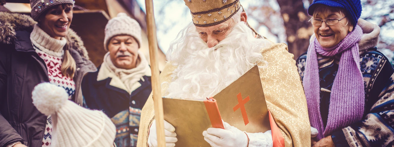 EIn Nikolaus liest einem Kind aus seinem goldenen Buch vor