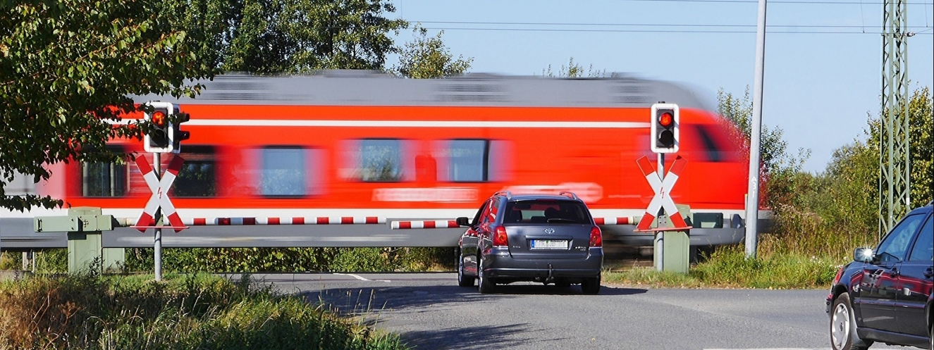 Ein fahrender Zug am Bahnübergang