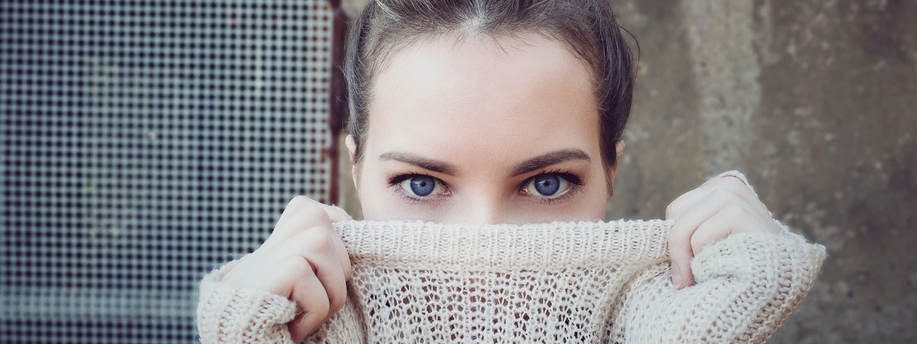 Eine Frau verdeckt ihr Gesicht hinter einem Pullover