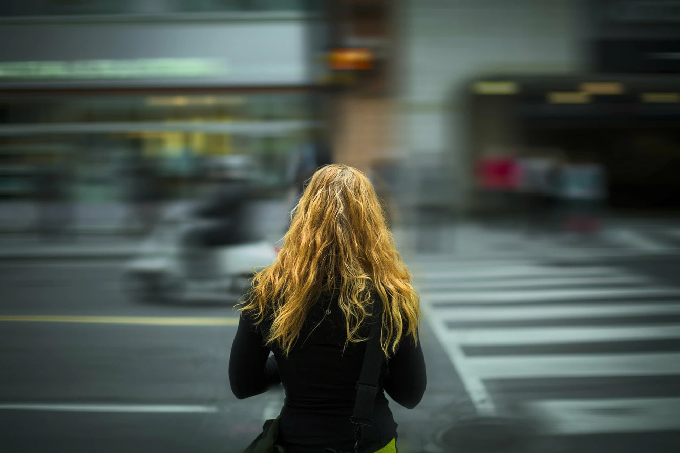 Eine junge Frau steht an der Straße und beobachtet den Verkehr
