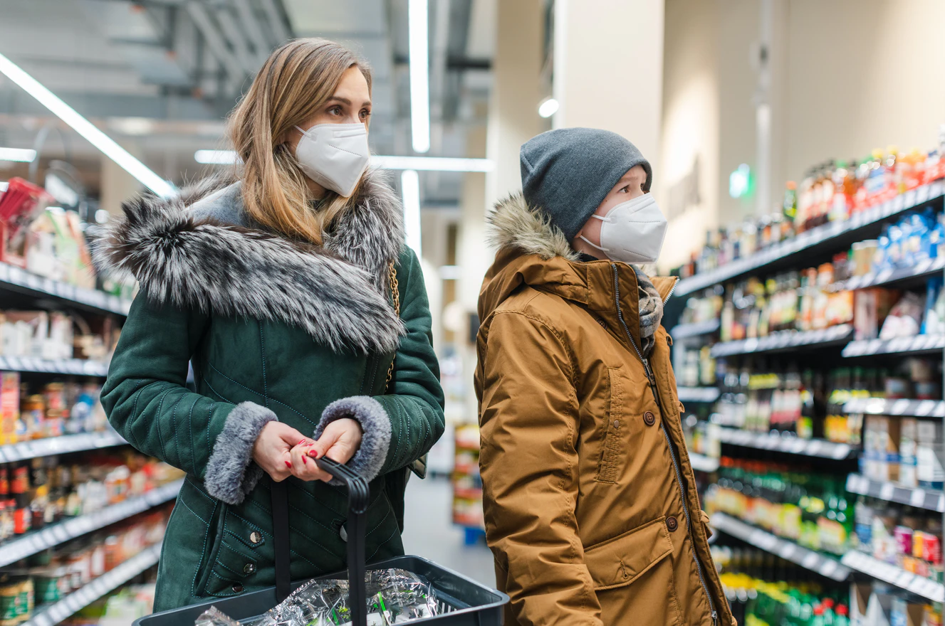 Mutter und Sohn mit maske beim einkaufen