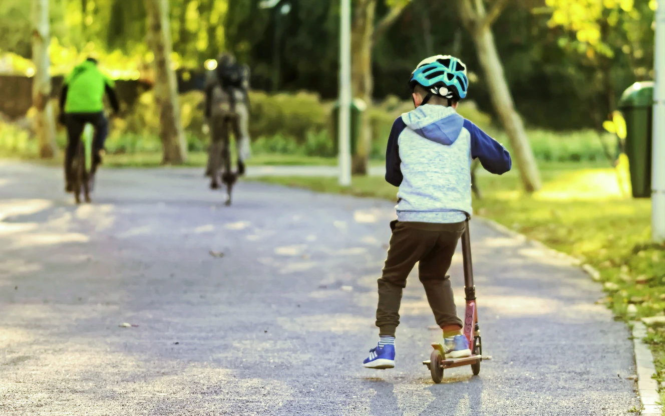 Kind mit einem Roller auf der Straße