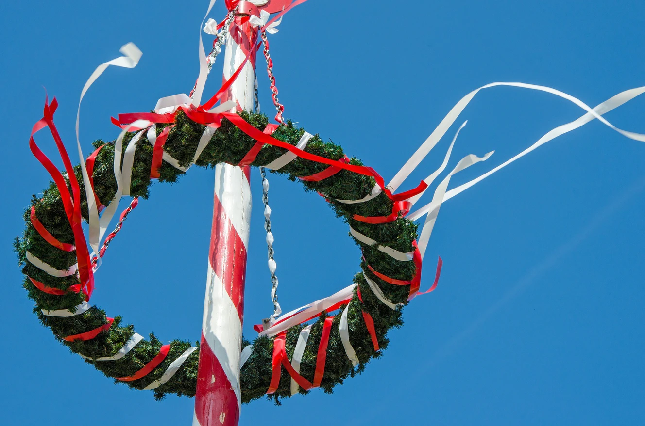 Maibaum mit Kranz und roten Bändeln