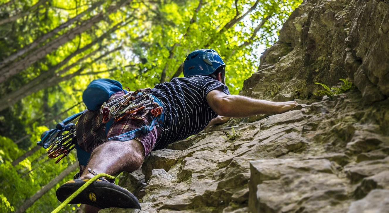 Ein Kletterer klettert angekettet einen Felsen hoch
