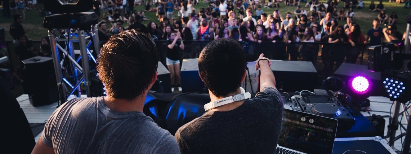 Zwei DJs stehen auf einer Bühne vor Publikum — © Symbolbild
