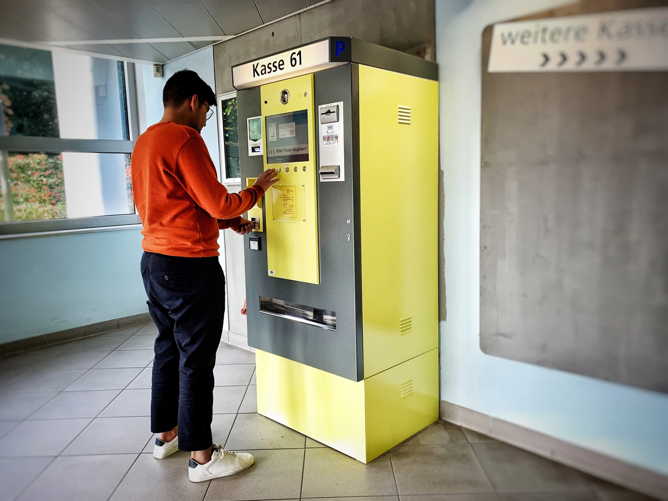 Jemand, der ein Parkticket am Automaten bezahlt
