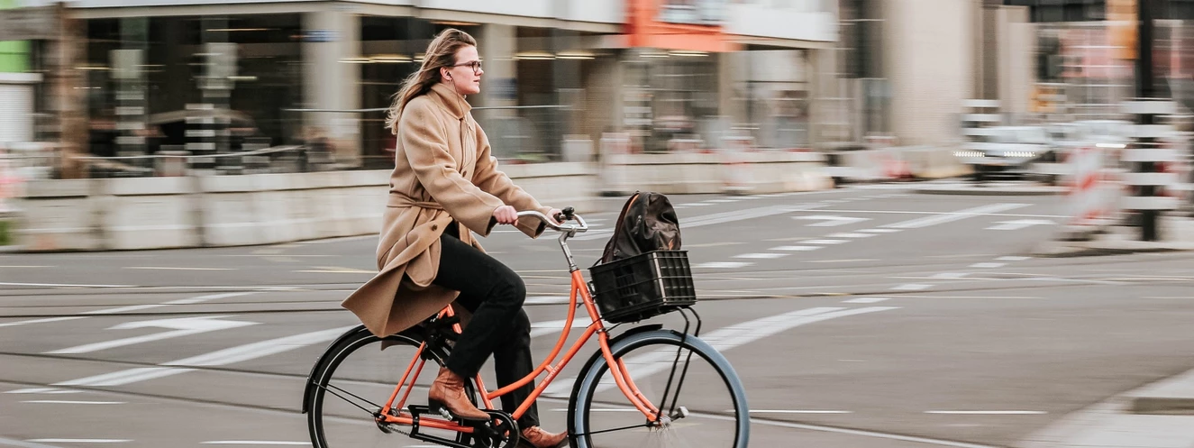 Eine Frau fährt auf einem Fahrrad mit Fahrradkorb über die Straße