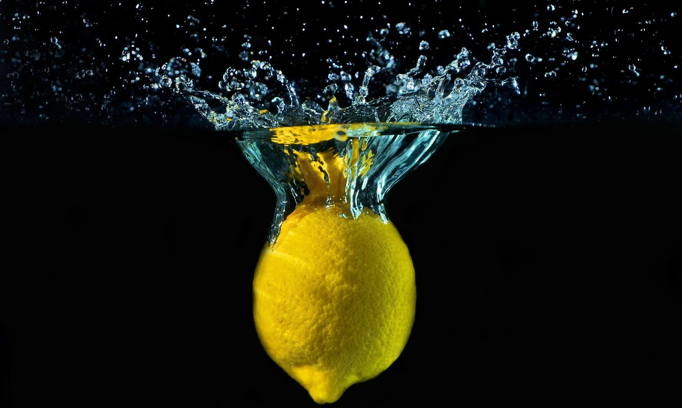 Zitrone, die in Wasser geworden wird und erfrischend spritzt