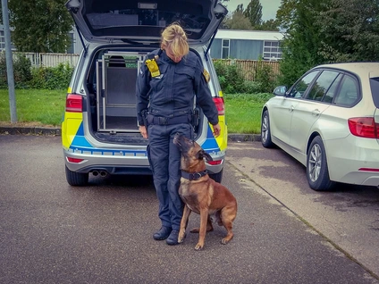 Polizei-Beamtin in Uniform mit Body-Cam und Hund